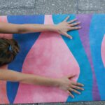 A woman engaged in yoga with a colorful mat and smartphone nearby, promoting wellness.